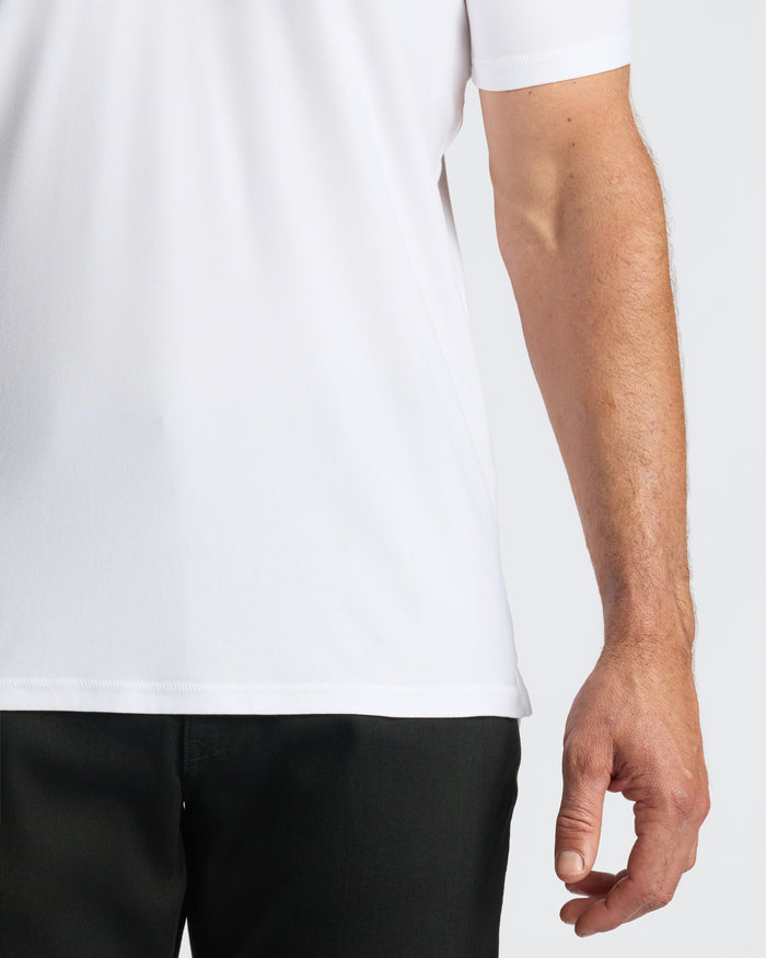 White Active Polo worn with black pants, showcasing short sleeves and fit.