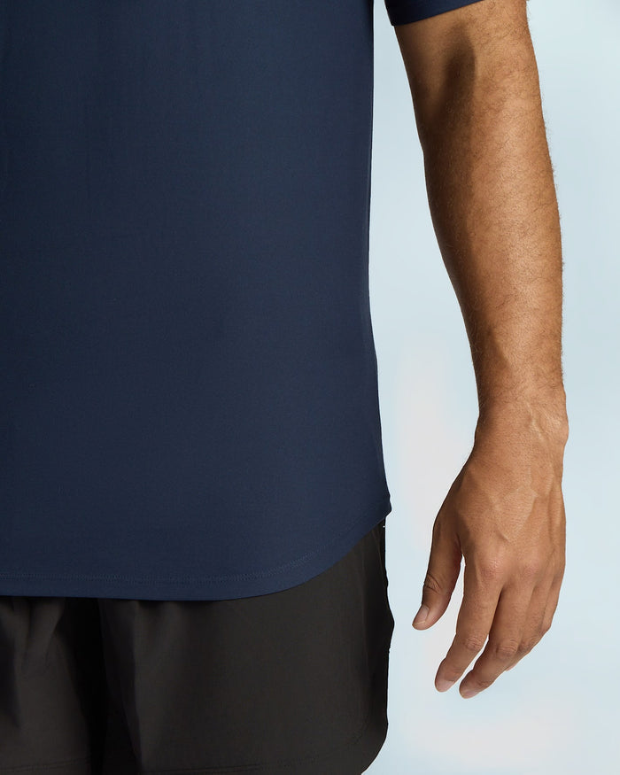 Person wearing a navy blue shirt and black shorts on a light gray background