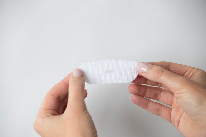 model holding in both hands a single strip of oi tape vented mouth tape