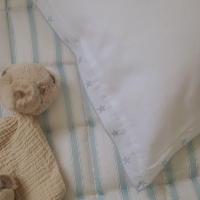 Beige teddy bear on a blue striped playmat