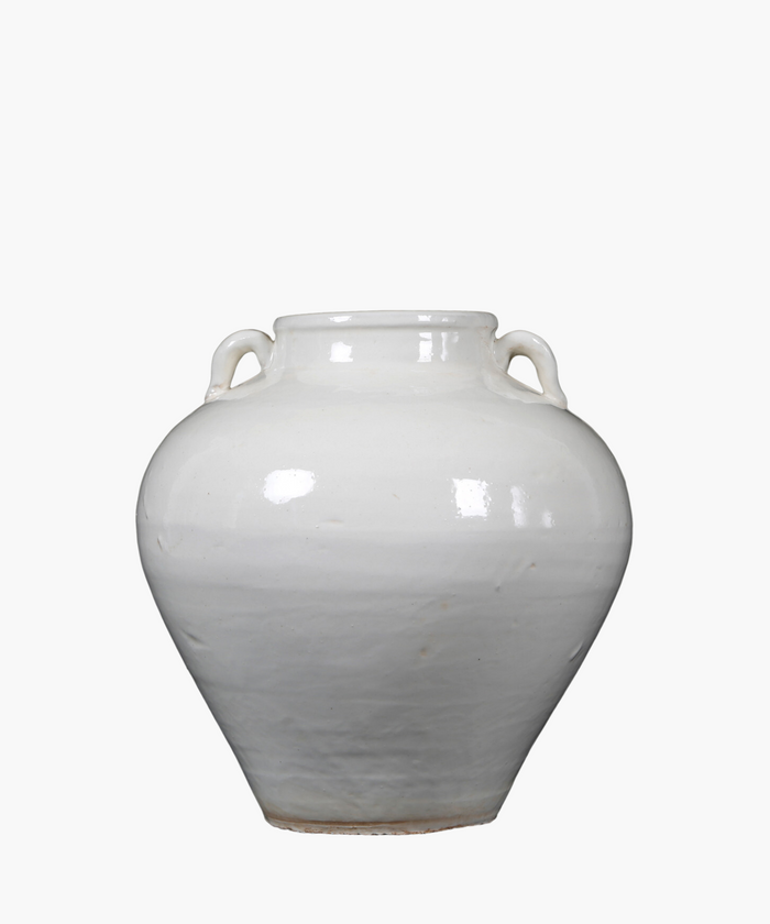 A simple, antique inspired white ceramic vase with two small handles near the neck, reflecting light softly, set against a plain white background. | Wildwood Home Co.