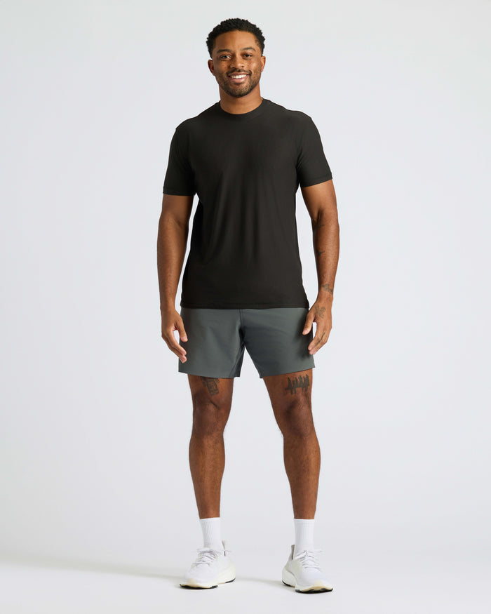 Young man wearing Black Active Crew Neck Tee, gray shorts, and white shoes.