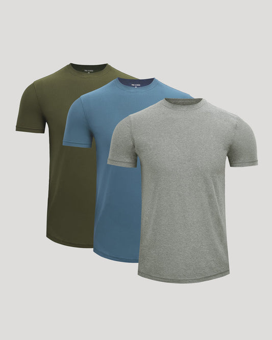 Three short-sleeve crew-neck t-shirts in olive green, blue, and heather gray, arranged in a layered fan display against a light gray background.