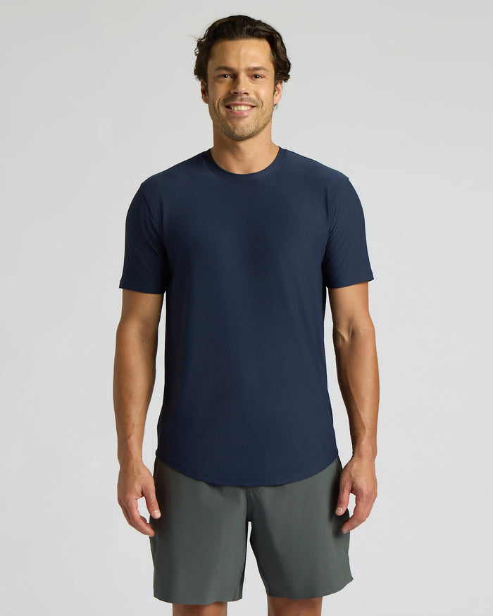 Man wearing a navy blue t-shirt and gray shorts on a light gray background