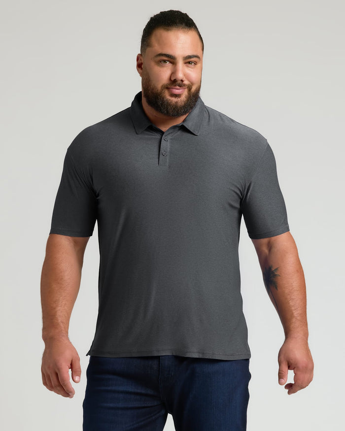 Man wearing a charcoal heather gray polo shirt with short sleeves and a collar, paired with dark blue jeans, showcasing the Charcoal Heather Gray Active Polo 2.0.