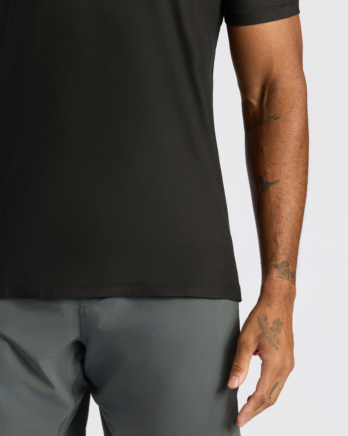 Person wearing Black Active Crew Neck Tee with tattooed forearm visible.