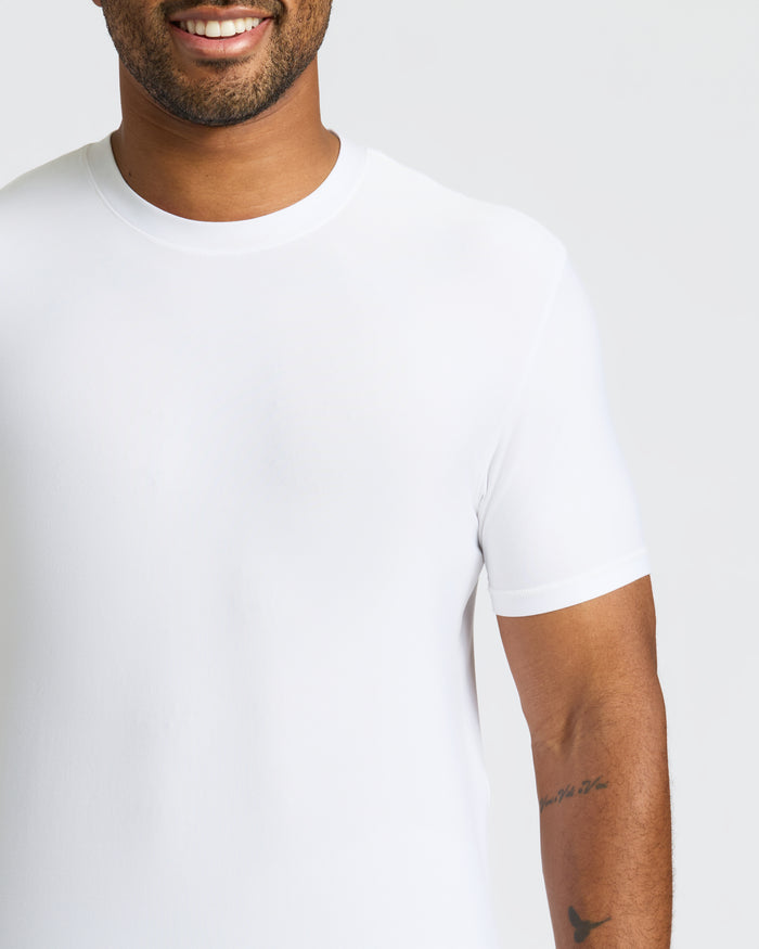 Man in White Active Crew Neck Tee with tattoos on forearm.