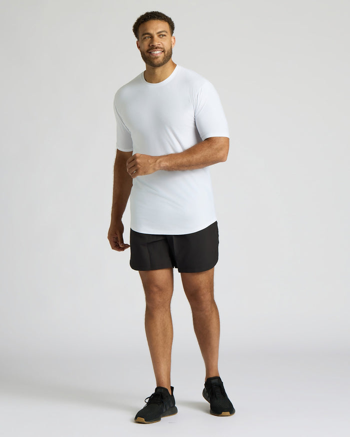 Man wearing a white t-shirt and black shorts on a light gray background