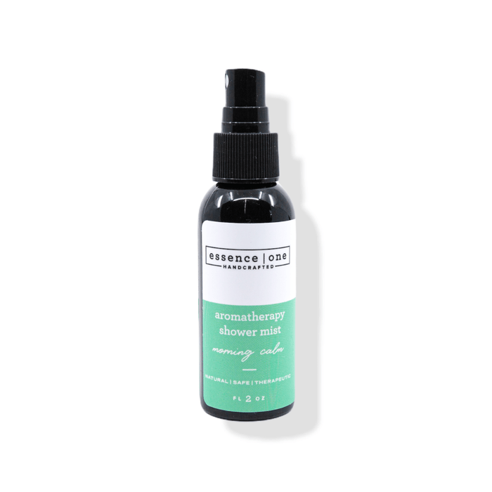 A black spray bottle of Aromatherapy Shower Mist | Essence One with a green and white label, designed for a calming wellness and body care experience.