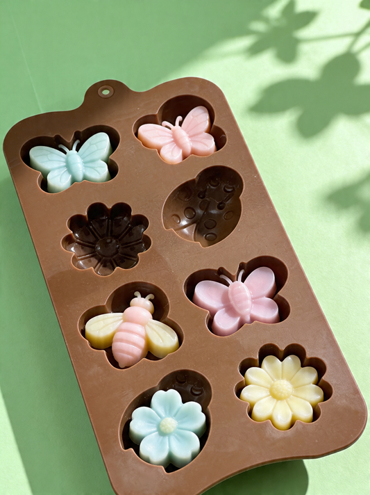 Silicone mold with butterfly, flower, and bee shapes on a green background