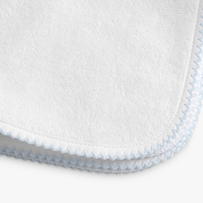 Close-up of a white textured fabric with blue stitching on a white background