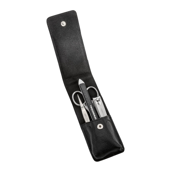 Essential Grooming Kit | Tweezerman featuring stainless steel nail clippers, scissors, tweezers, and a nail file neatly arranged in a black leather case for on-the-go grooming.