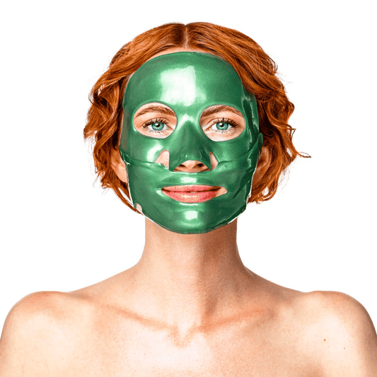 A person with red hair wearing a shiny green facial mask looking forward, showcasing the Green Jade Calm Face Mask | KNESKO designed for skincare and relaxation.