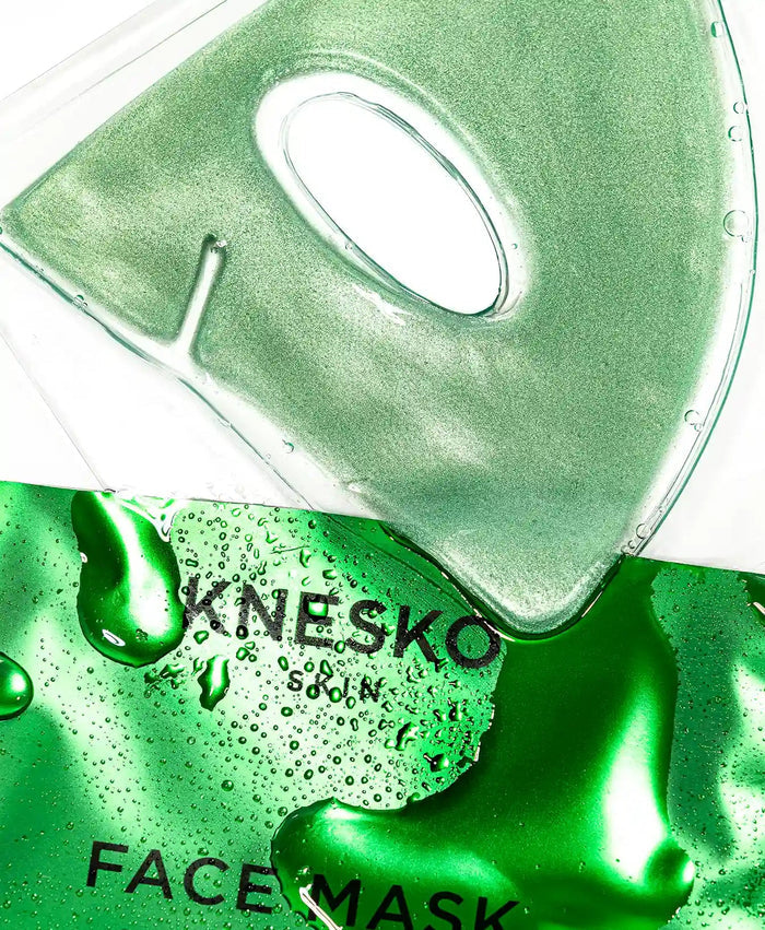 Close-up of a shimmering green gel face mask sheet with an eye cutout resting on its glossy green packaging labeled Green Jade Calm Face Mask | KNESKO, showcasing skincare and wellness.