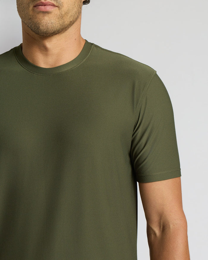 A close-up of a man wearing a solid olive green crew-neck t-shirt against a light gray background.