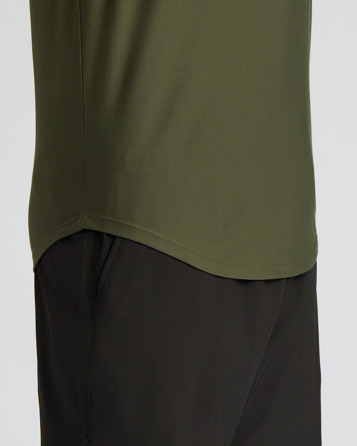 Close-up of a person wearing an olive green athletic top and black shorts against a light gray background.