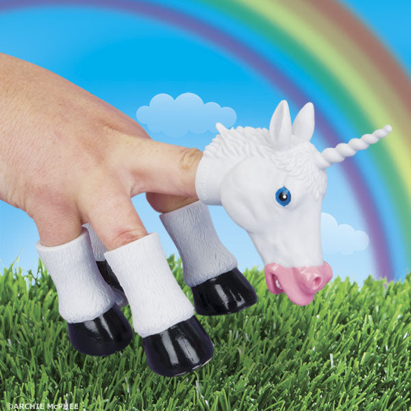 Fingers encased in the Handicorn, complete with a unicorn head puppet and hoof covers, wander through the grass against a vivid rainbow backdrop.
