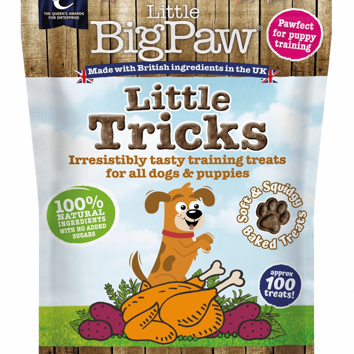 White background with a close up of a packet of Little BigPaw 'Little Tricks' dog treats. Pictured on the packet is an illustration of a brown dog with a cooked chicken and vegetables in the foreground. Text on the bag says 'Irresistibly tasty training treats for all dogs & puppies, 100% natural ingredients, soft & squidgy baked treats. Approx. 100 treats!'
