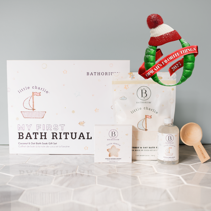 little charlie™ My First Bath Ritual Gift Box Set | Bathorium displayed with bath soak, bath salt, body wash, wooden scoop, and an Oprah’s Favorite Things 2023 wreath in the background.