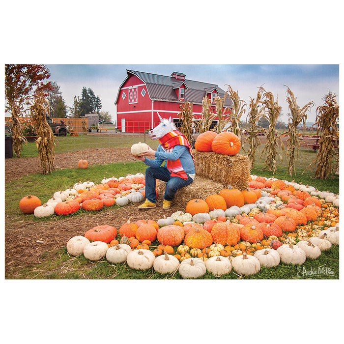 A person wearing a unicorn mask sits on hay bales amidst pumpkins, with a red barn in the background, creating an enchanting scene reminiscent of the "Lord Unicorn and His Pumpkin Kingdom Puzzle.