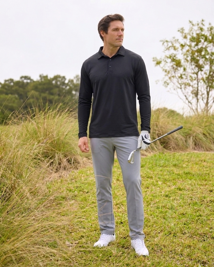 Man in black shirt and gray pants holding a golf club on a grassy field