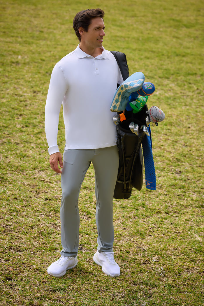 Man standing on a grassy field holding golf clubs.