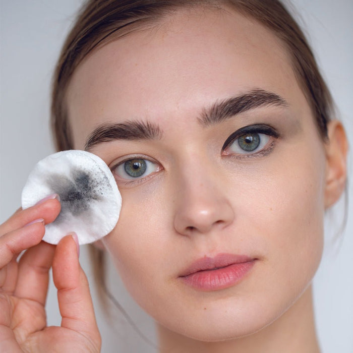 Woman removing eye makeup with cotton pad, showcasing gentle skincare routine for clean, radiant skin