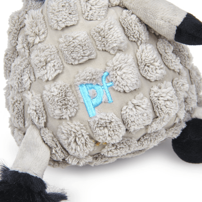 Close up of grey donkey dog toy with back tail and hoofs wearing a blue neckerchief, focus on stitch detail of 'PF' on back sat on a white background.