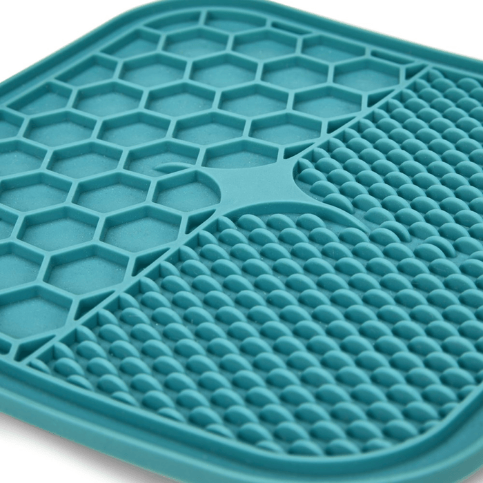 Close up of blue silicone lick mat with two different textures, one with hexagon shapes, the other with small close together ridges pictured on a white background.