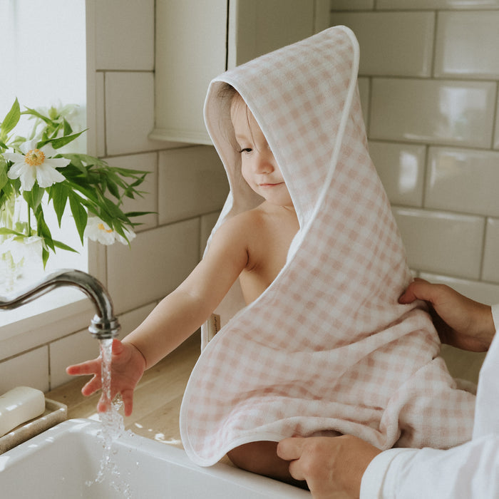 Child wrapped in a checkered towel in a bathroom setting