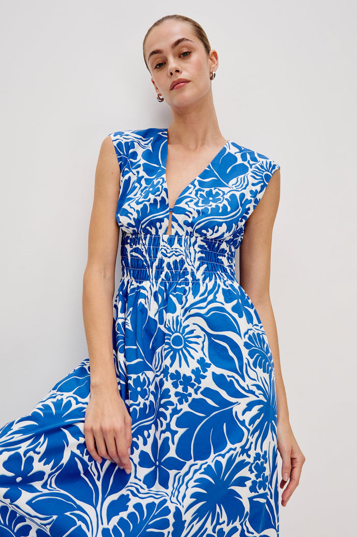 Roxanne A-Line Midi Dress with Smocked Waist, V-Neck, Cap Sleeve and Side Pockets in Blue Riviera Colorway. Front View Shown on Model.