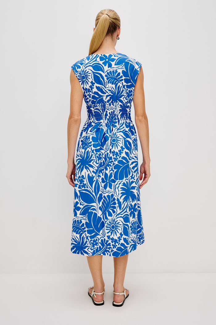 Roxanne A-Line Midi Dress with Smocked Waist, V-Neck, Cap Sleeve and Side Pockets in Blue Riviera Colorway. Full Body Back View Shown on Model.