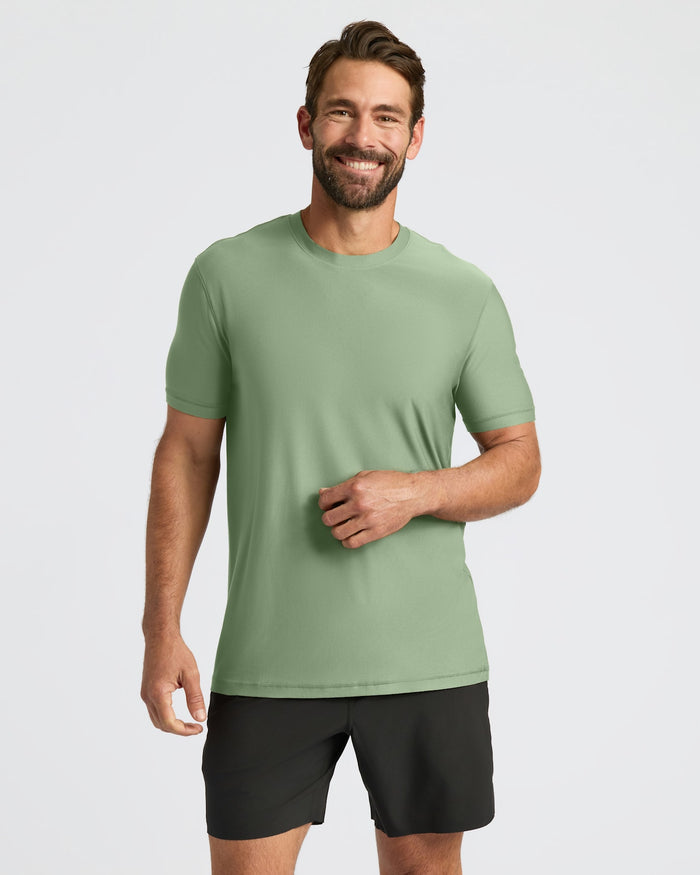 Man wearing a green t-shirt and black shorts on a light gray background