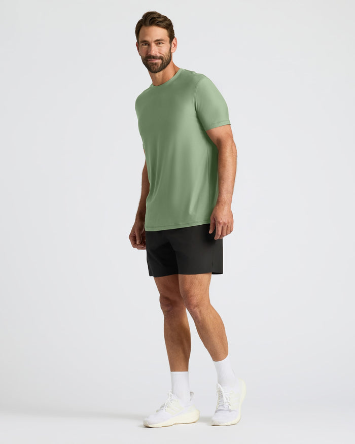 Man wearing a green t-shirt and black shorts on a white background