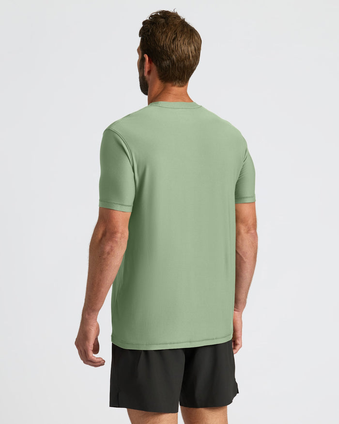 Man wearing a green t-shirt and black shorts on a light gray background