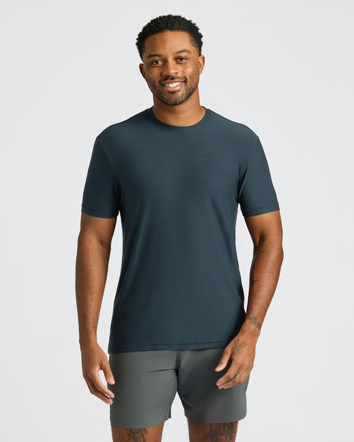 Man wearing a dark blue t-shirt and gray shorts on a light gray background