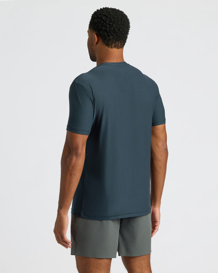 Man wearing a dark blue t-shirt and gray shorts on a light gray background