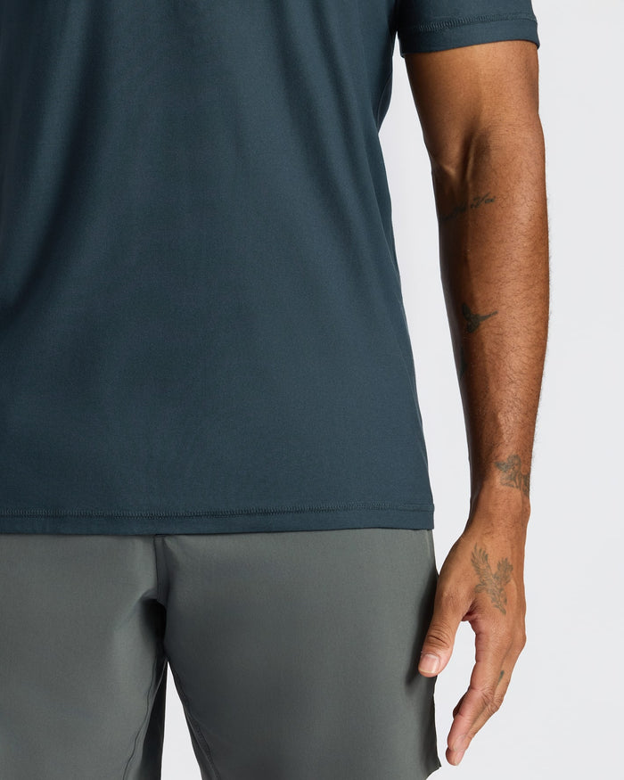 Person wearing a dark green t-shirt and gray pants on a white background
