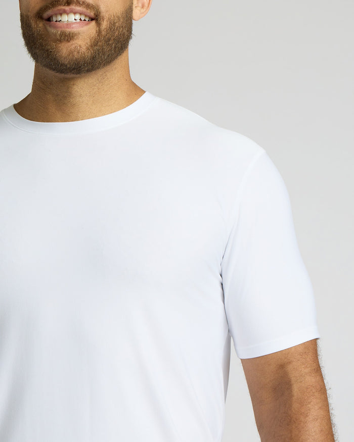 Man wearing a plain white t-shirt against a light gray background